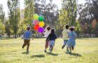 children playing with balloons on green grass field